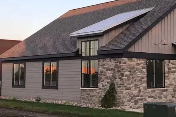 Ranch home with brown board-and-batten siding, stone veneer and solar panels on the roof